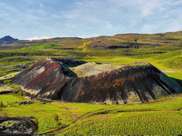 una vista aérea de un volcán colorido en medio de un campo verde .