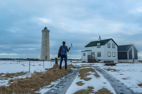 Man taking a picture of a white lighthouse