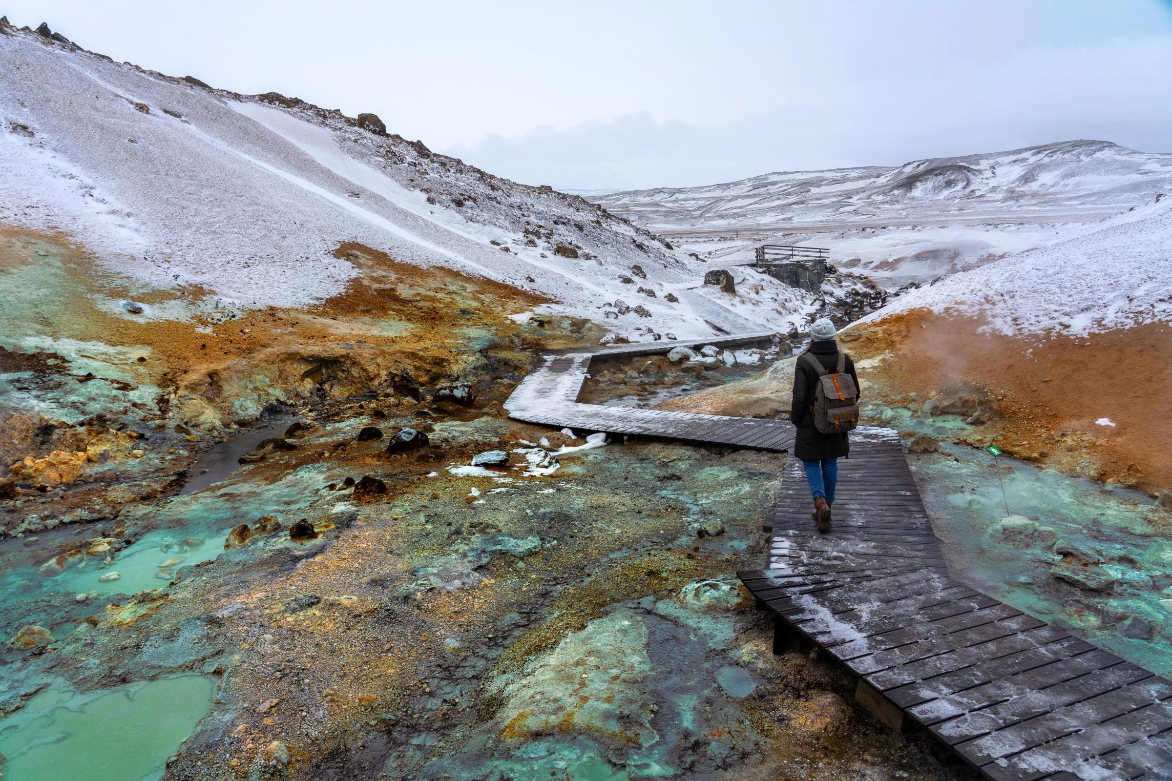 a person is walking across a wooden bridge over a river .