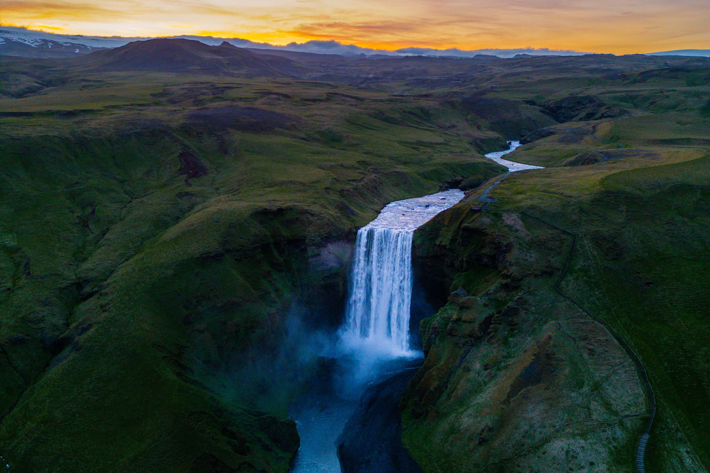an aerial view of a waterfall at sunset in iceland .