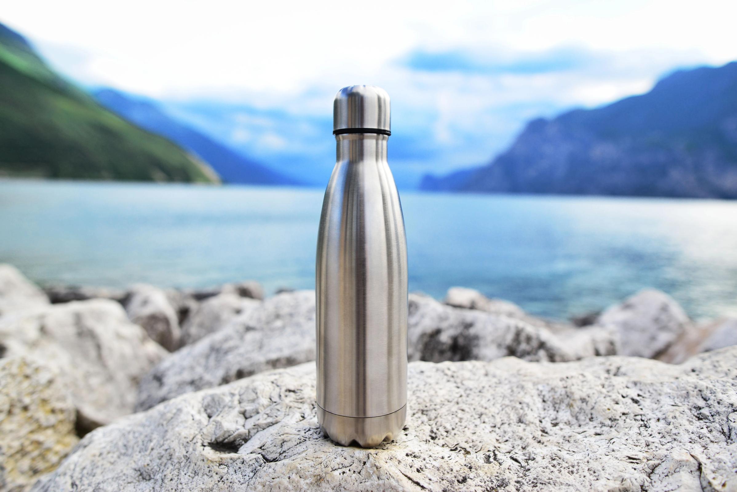 Close-up of a steel thermosensitive water bottle on a lake background in the middle of the Icelandic mountains. Zero waste. 