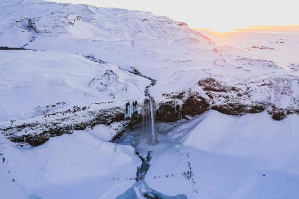 an aerial view of a waterfall in the middle of a snowy mountain .