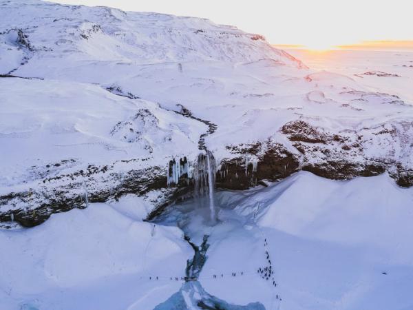 an aerial view of a waterfall in the middle of a snowy mountain .
