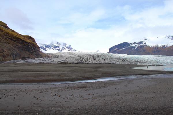a landscape with a glacier and mountains with snow on the peak