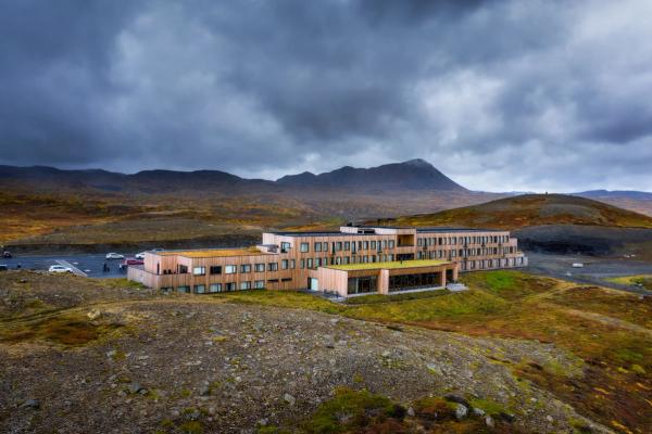 a large building is sitting on top of a hill with mountains in the background .
