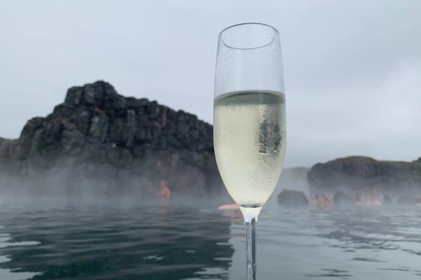 a person is holding a glass of champagne in front of a hot spring .