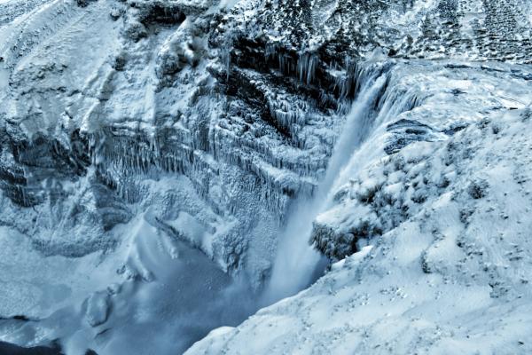 a waterfall in the middle of a snowy mountain covered in snow and ice at skógafoss in iceland.