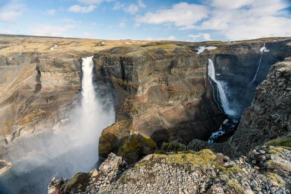 a waterfall is coming down a cliff in the middle of a canyon at hái and granni foss in iceland.