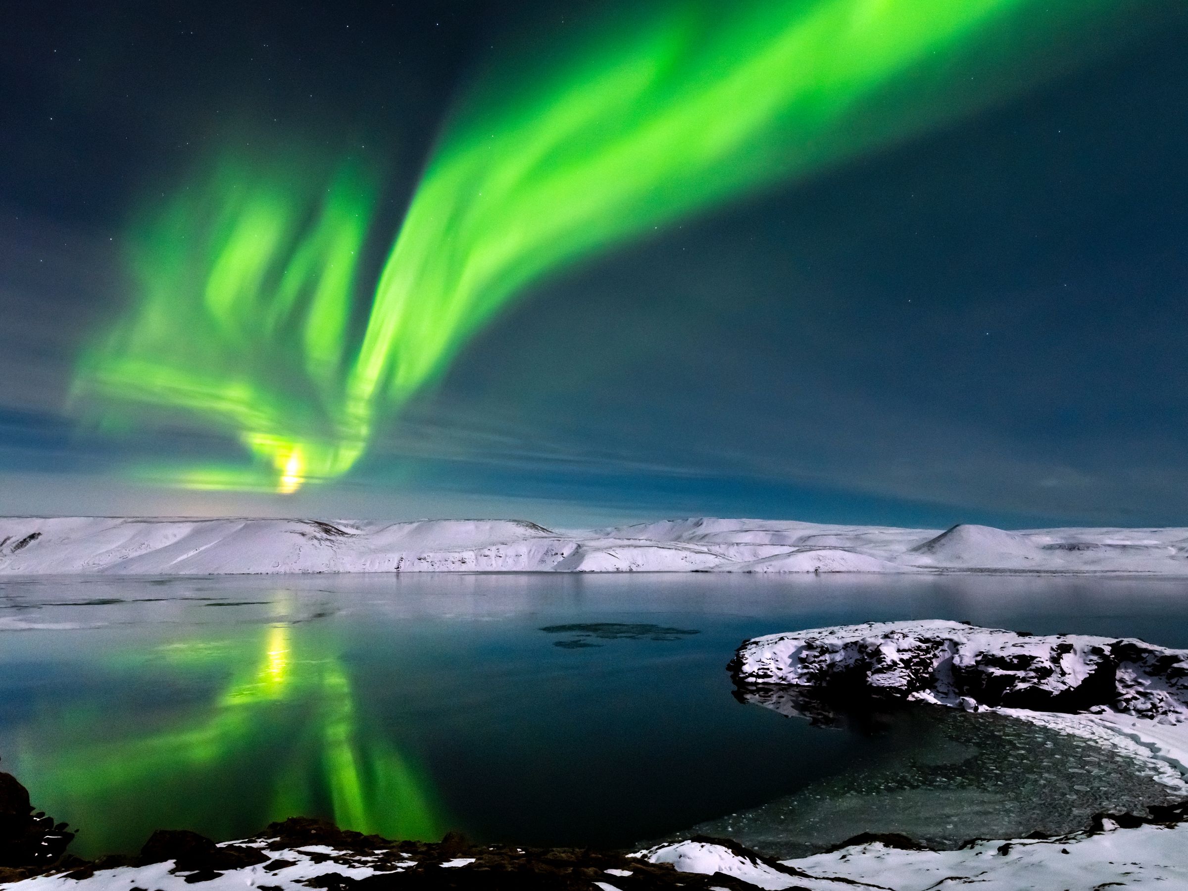 un lago rodeado de nieve con la Aurora Boreal encima