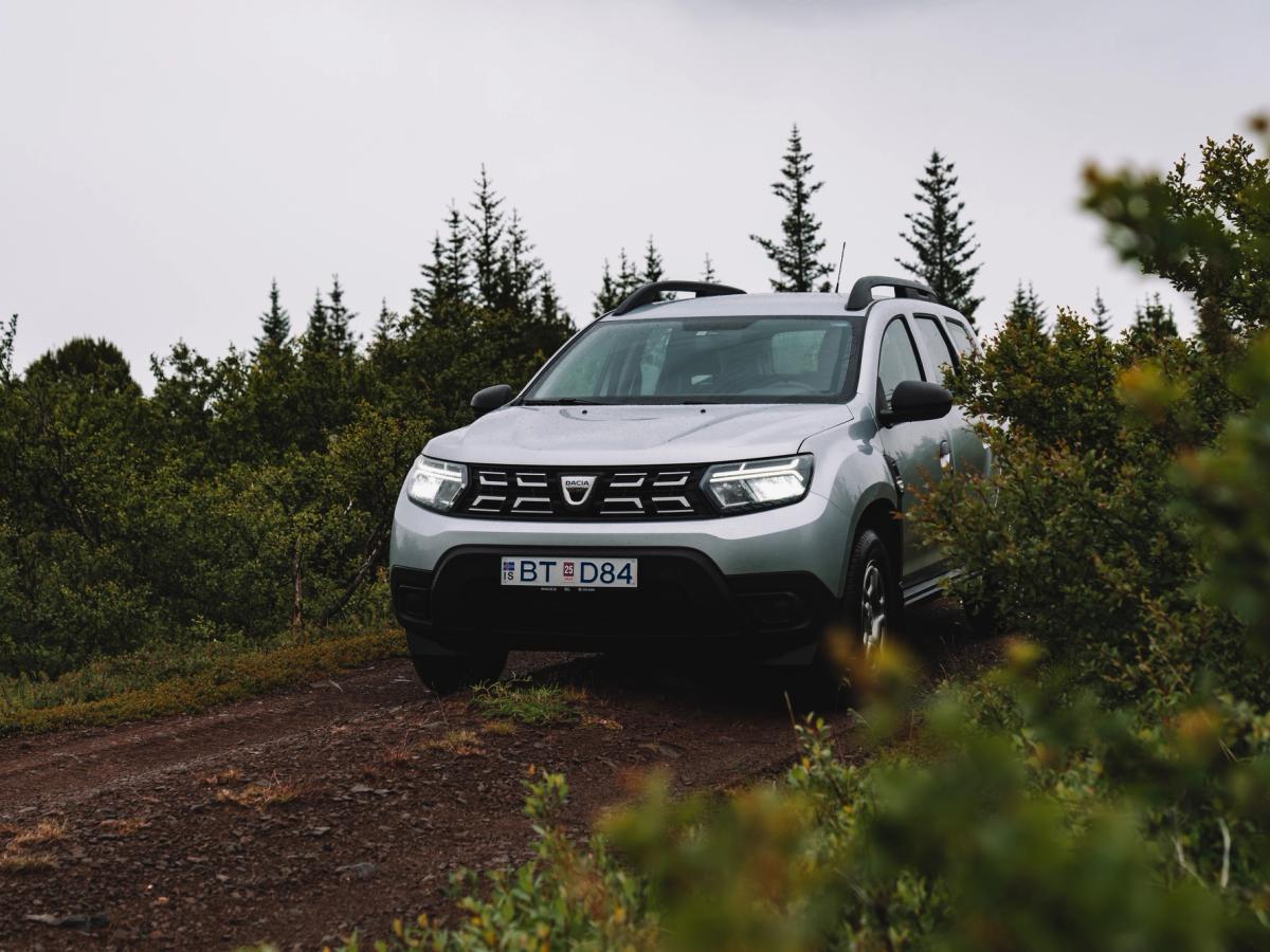 Vista del Dacia Duster en un sendero forestal Dacia Duster aparcado en un camino de tierra rodeado de pinos y arbustos