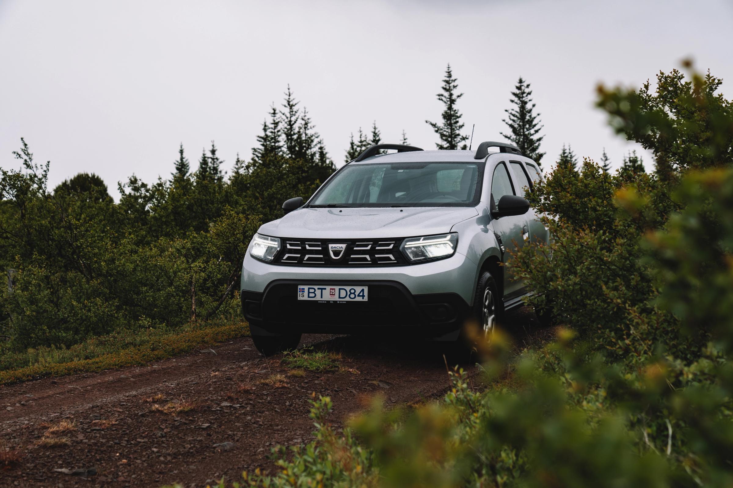 Vista del Dacia Duster en un sendero forestal Dacia Duster aparcado en un camino de tierra rodeado de pinos y arbustos