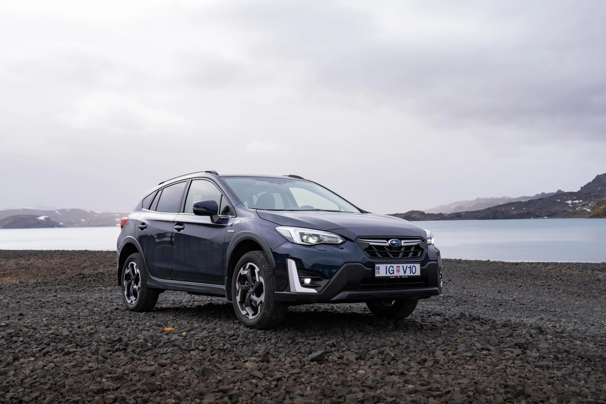 冰岛租赁的斯巴鲁 XV SUV 停在湖边的碎石地上，远处群山环绕