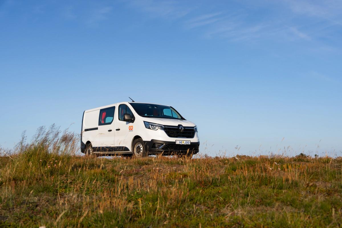 A medium camper that sleeps 3 people parked on a grassy hilltop, camper van rental Iceland