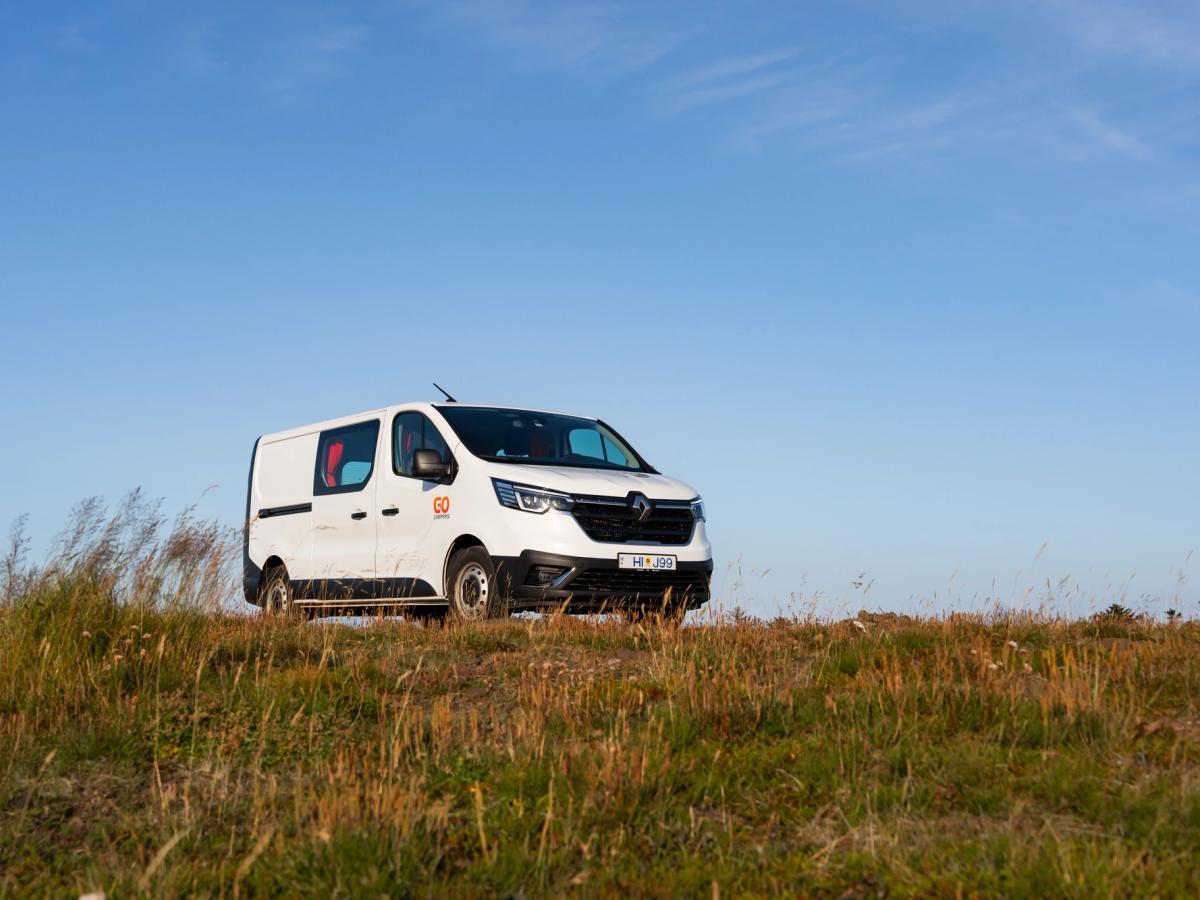 Camper mediano en ángulo bajo Vista en contrapicado de una autocaravana mediana con capacidad para 3 personas sobre una cresta, alquiler de autocaravanas en Islandia