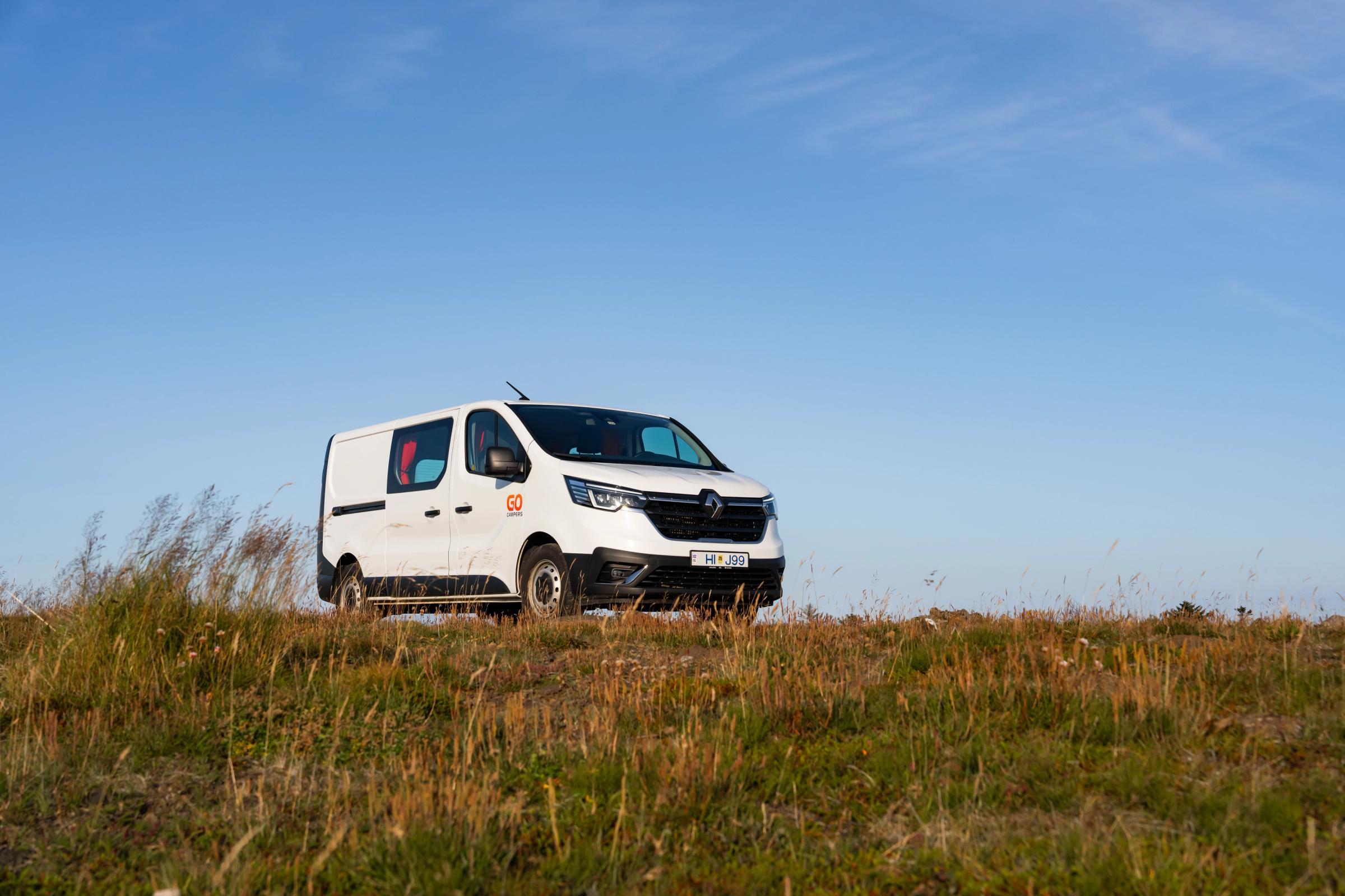 Camper mediano en ángulo bajo Vista en contrapicado de una autocaravana mediana con capacidad para 3 personas sobre una cresta, alquiler de autocaravanas en Islandia