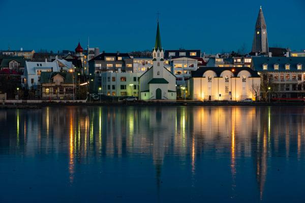 the buildings of a city reflected in the water at night