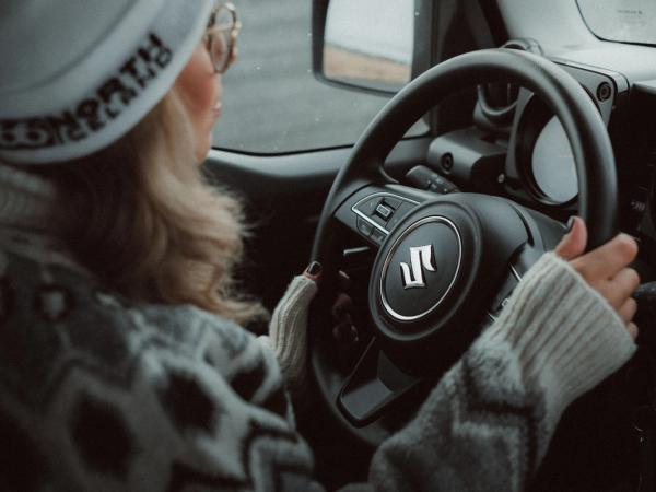 Girl with hat and glasses driving a Suzuki