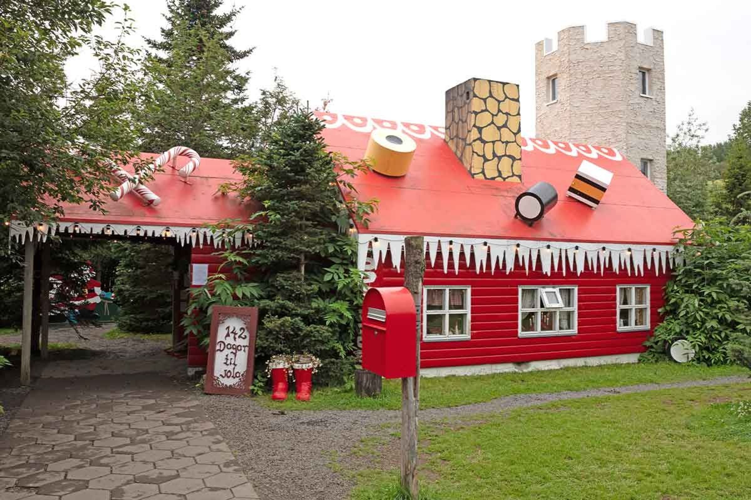 a red house with a candy cane on the roof and a mailbox in front of it .