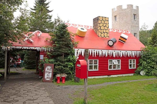 a red house with a candy cane on the roof and a mailbox in front of it .