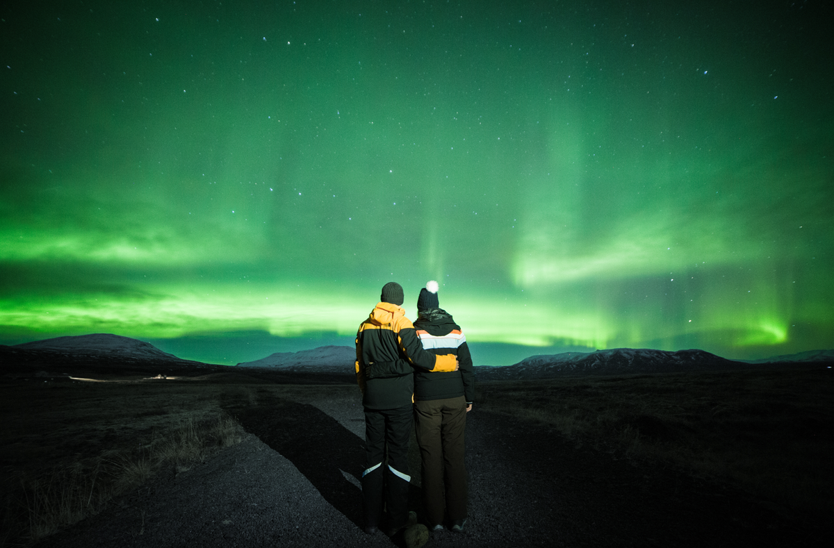 Un hombre y una mujer mirando la aurora boreal.