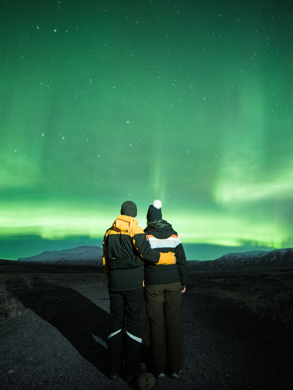 Un hombre y una mujer mirando la aurora boreal.