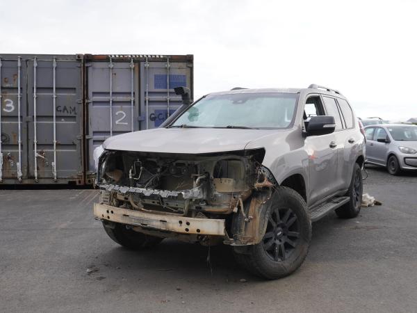 a damaged suv is parked in a parking lot next to a shipping container .