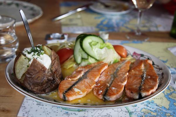 a plate of food with salmon , potatoes and vegetables on a table .