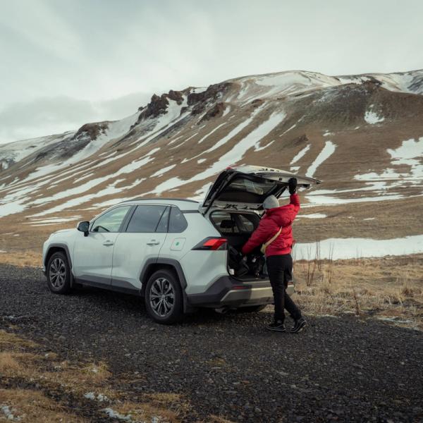 a man is loading luggage into the back of a white SUV .