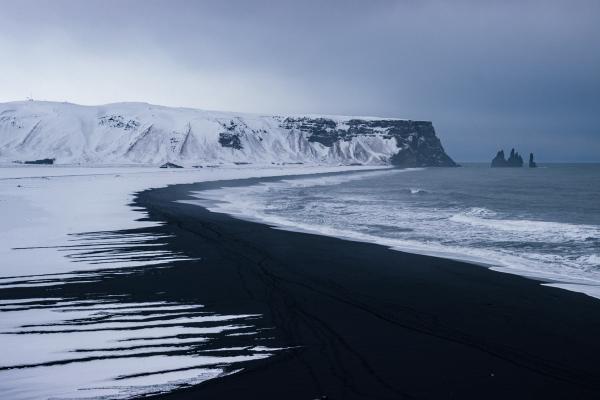 a black sand beach with snow