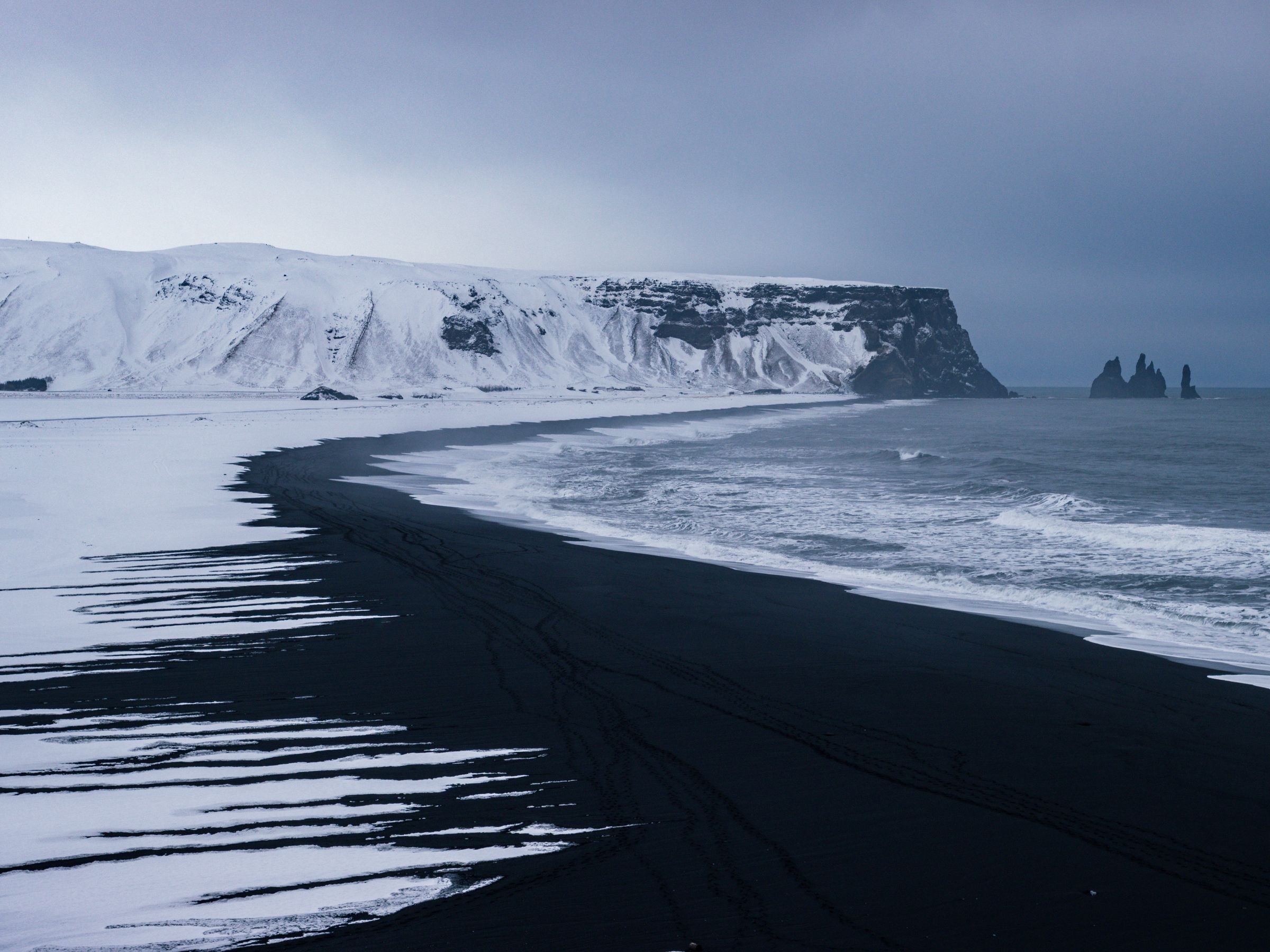 a black sand beach with snow