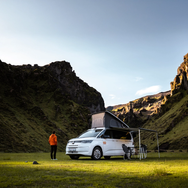 un hombre está parado frente a una furgoneta que dice 'camper' en la parte superior