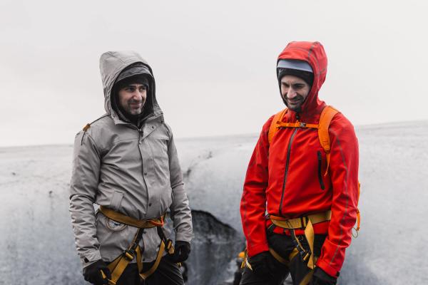 two men are standing next to each other on top of a mountain .