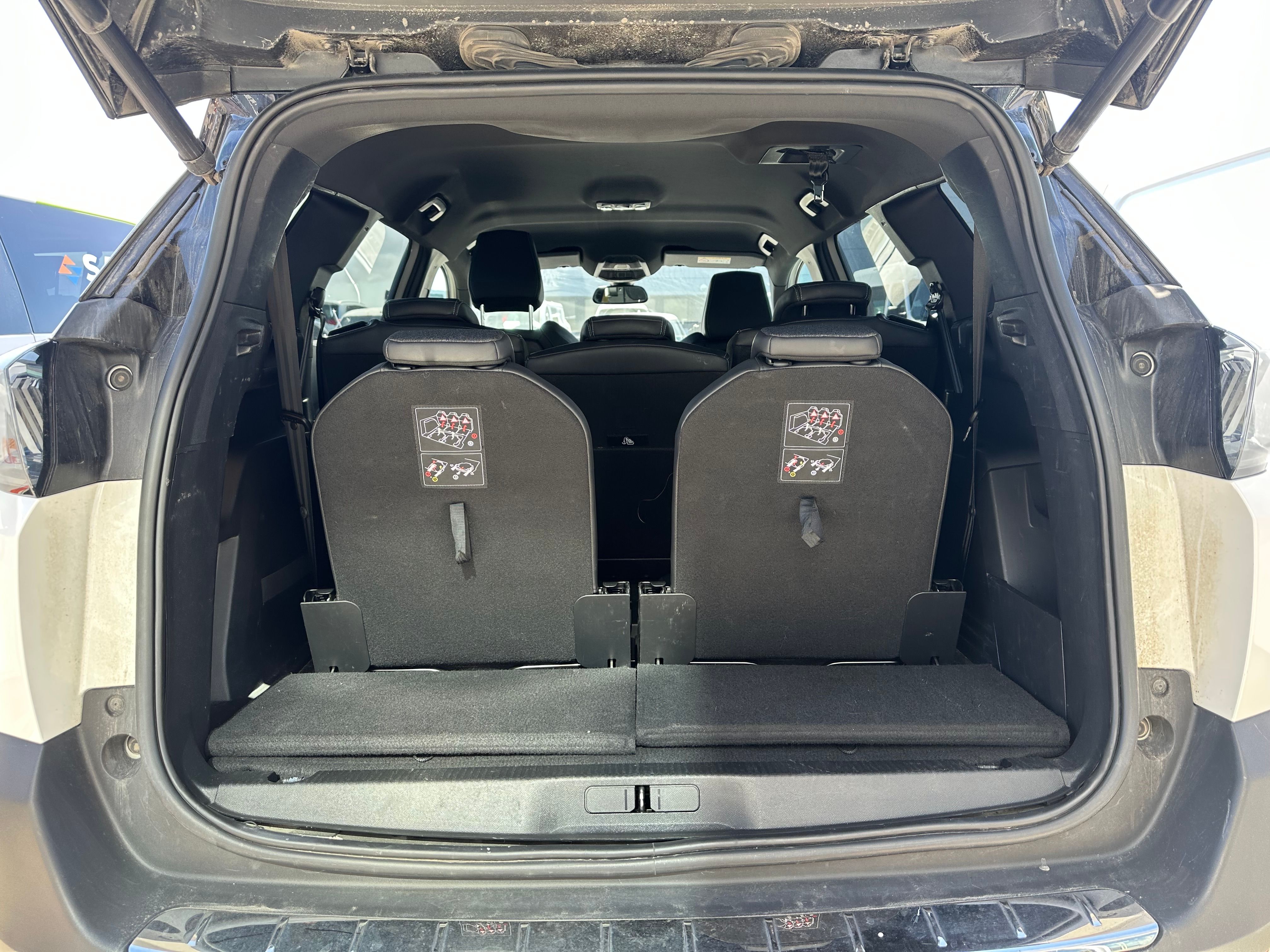 The open trunk of a car with the third-row seats folded flat, creating a cargo space.