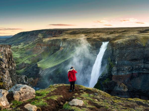 a person is standing on a cliff overlooking a waterfall .
