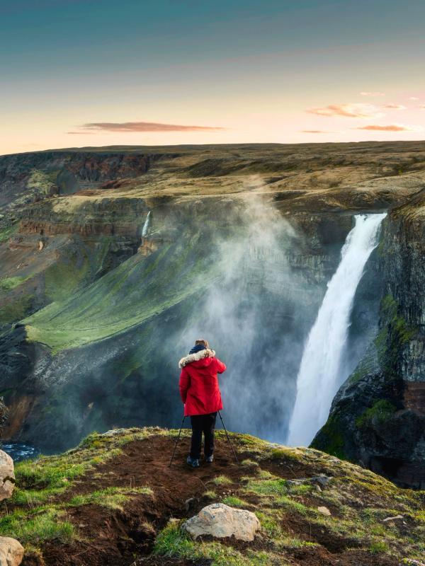Girl in a red jacket admiring Haifoss from a viewpoint