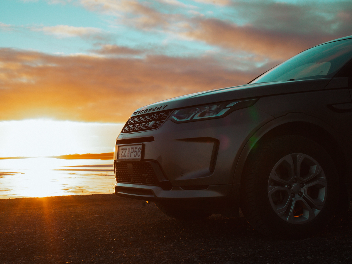 Discovery Sport – Frontansicht an der Küste Land Rover Discovery Sport 4x4 aus naher Frontperspektive, an einem offenen Gewässer geparkt