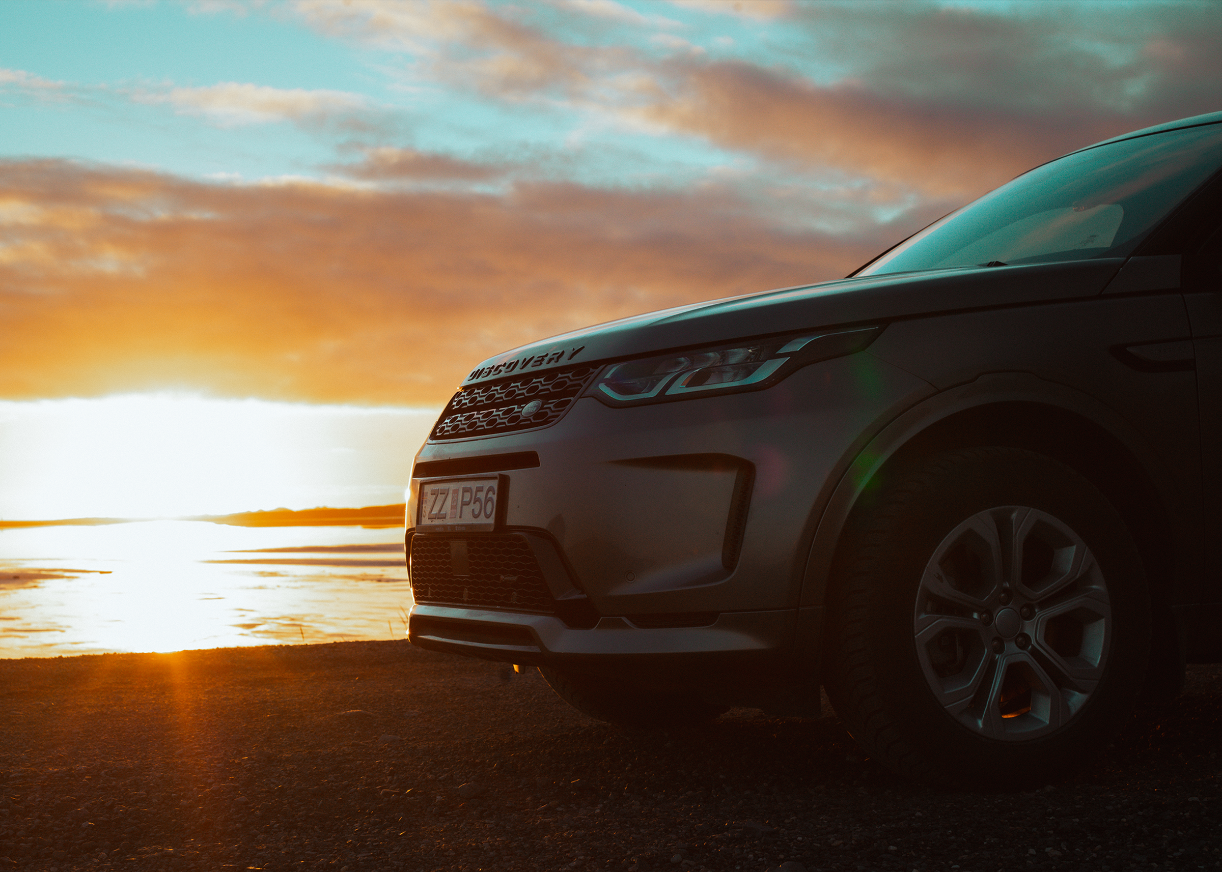 Discovery Sport – Frontansicht an der Küste Land Rover Discovery Sport 4x4 aus naher Frontperspektive, an einem offenen Gewässer geparkt