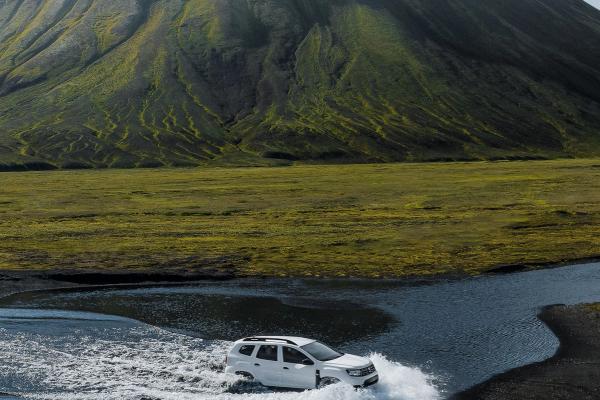 Dacia Duster crossing a river in Iceland Dacia Duster SUV crossing a river in an F-road in Iceland surrounded by mountain