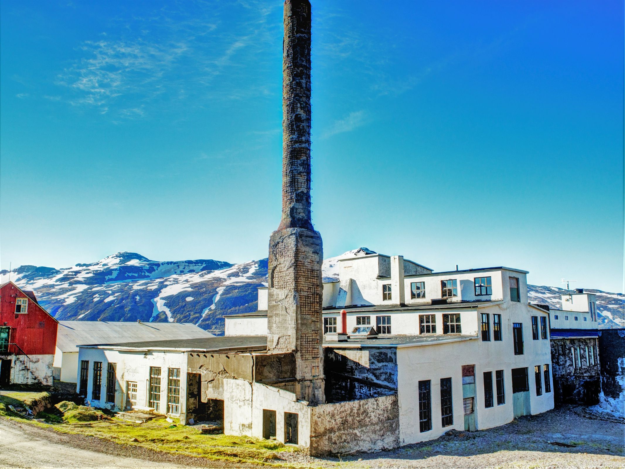 un grand bâtiment avec une cheminée devant et des montagnes en arrière-plan.