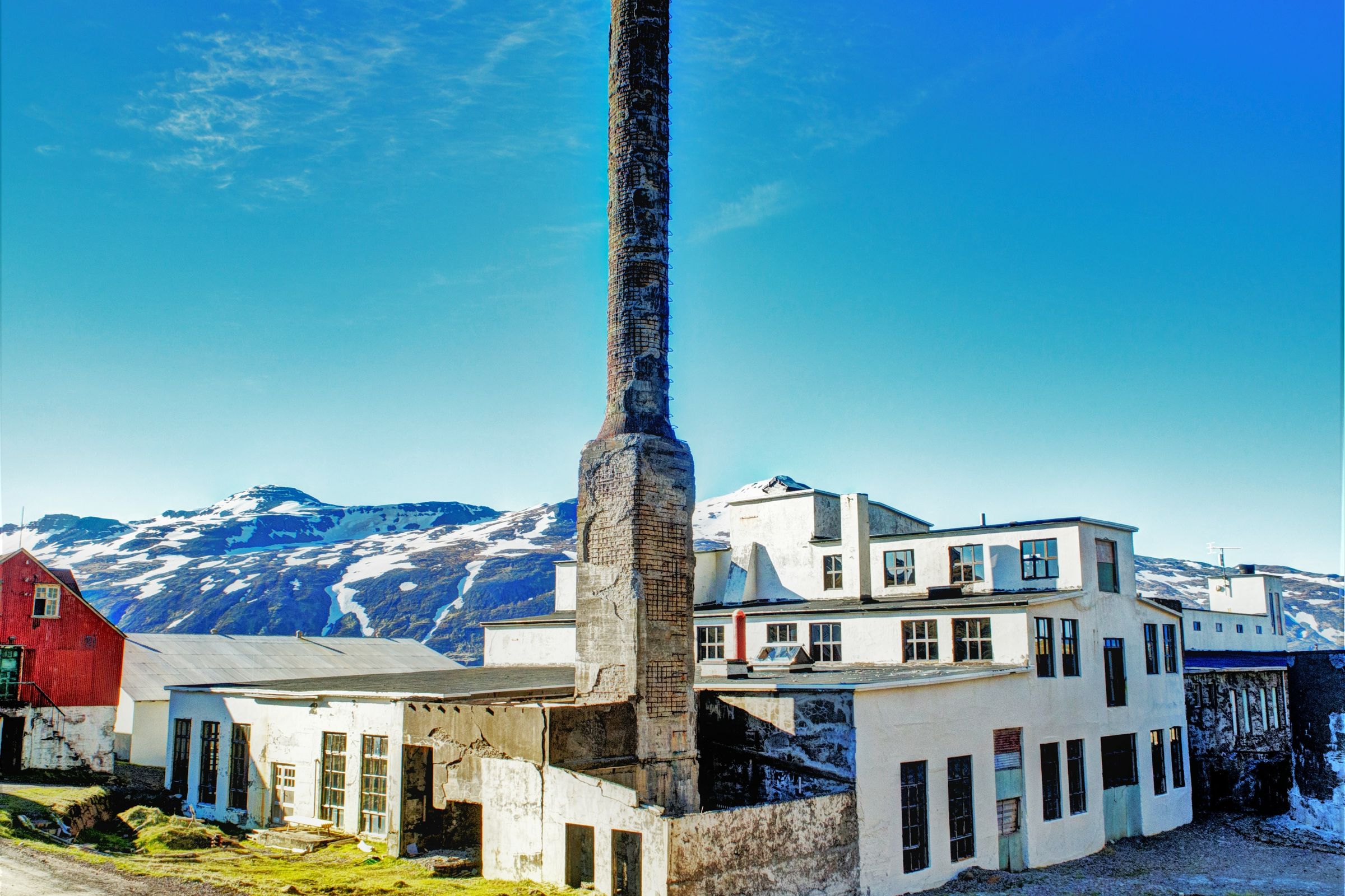 un grand bâtiment avec une cheminée devant et des montagnes en arrière-plan.