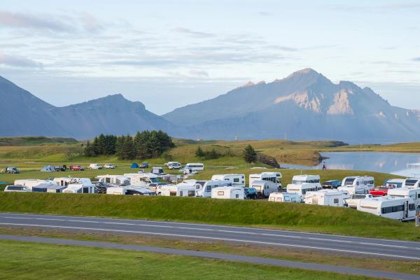 a campground with many campervans and mountains on the background