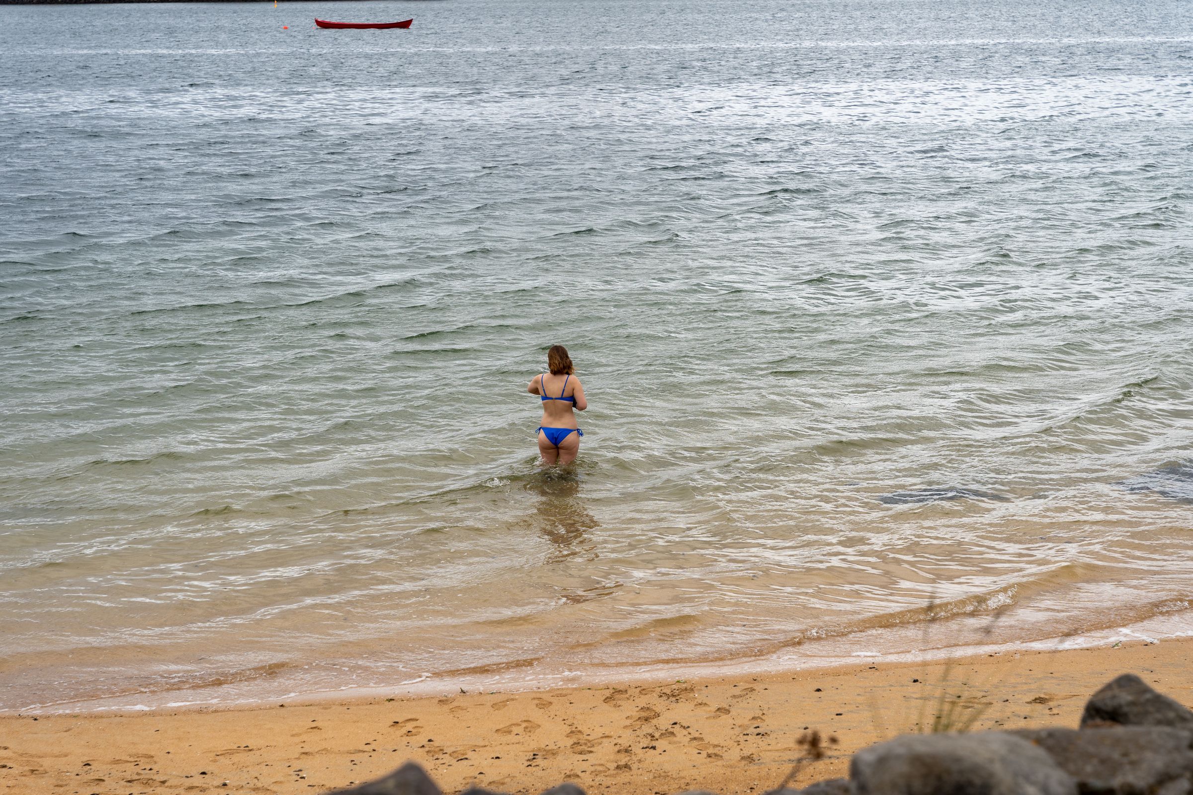 a woman in a bikini is walking out of the ocean .