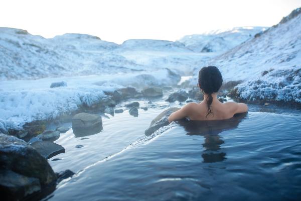 a woman is taking a bath in a hot spring in the mountains in iceland.