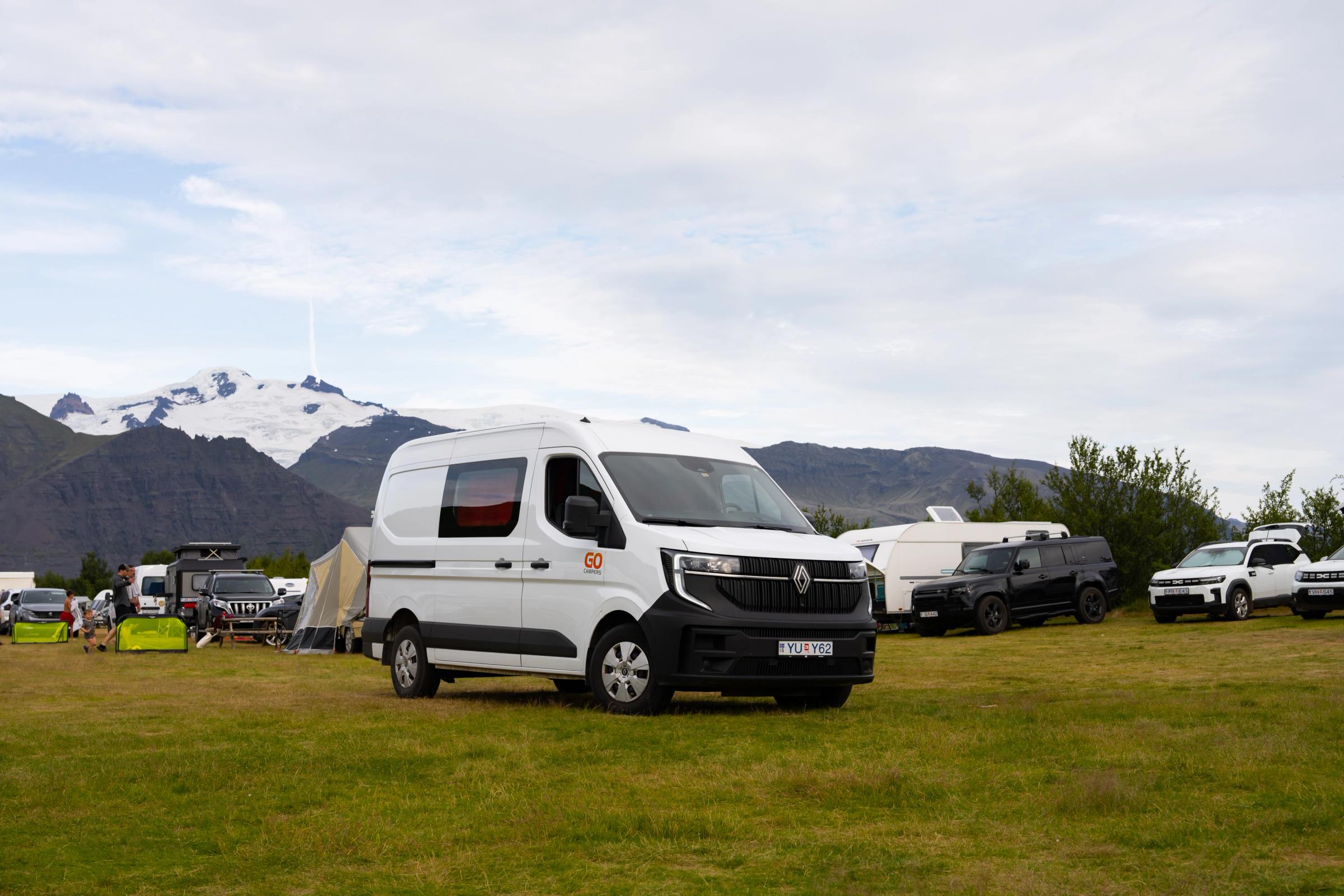 A large campervan that sleeps 5 among tents at a campsite, camper van rental Iceland