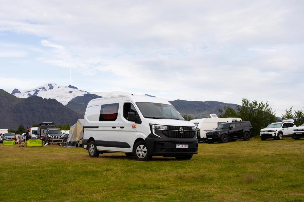 A large campervan that sleeps 5 among tents at a campsite, camper van rental Iceland