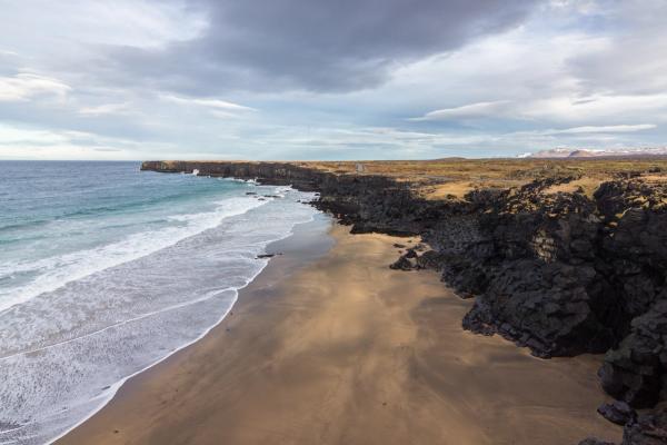 an aerial view of a sandy beach with waves crashing on the shore .