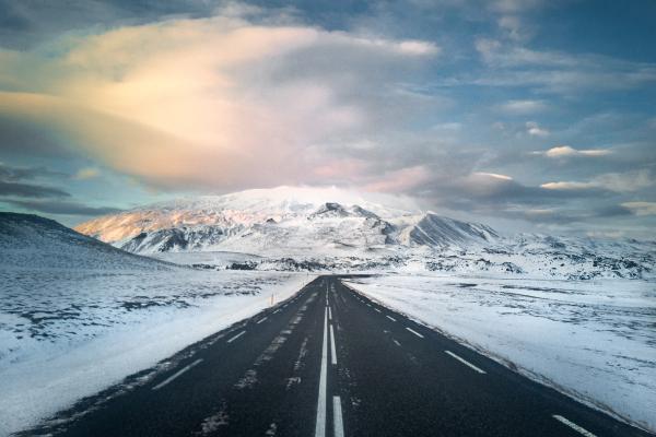 a road going through a snowy landscape with mountains in the background in iceland.