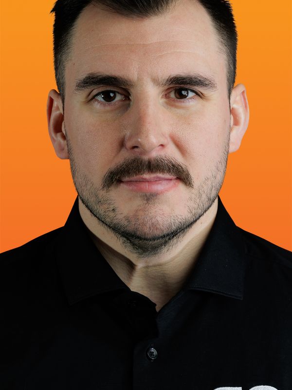 un homme avec une moustache porte une chemise noire qui dit GO