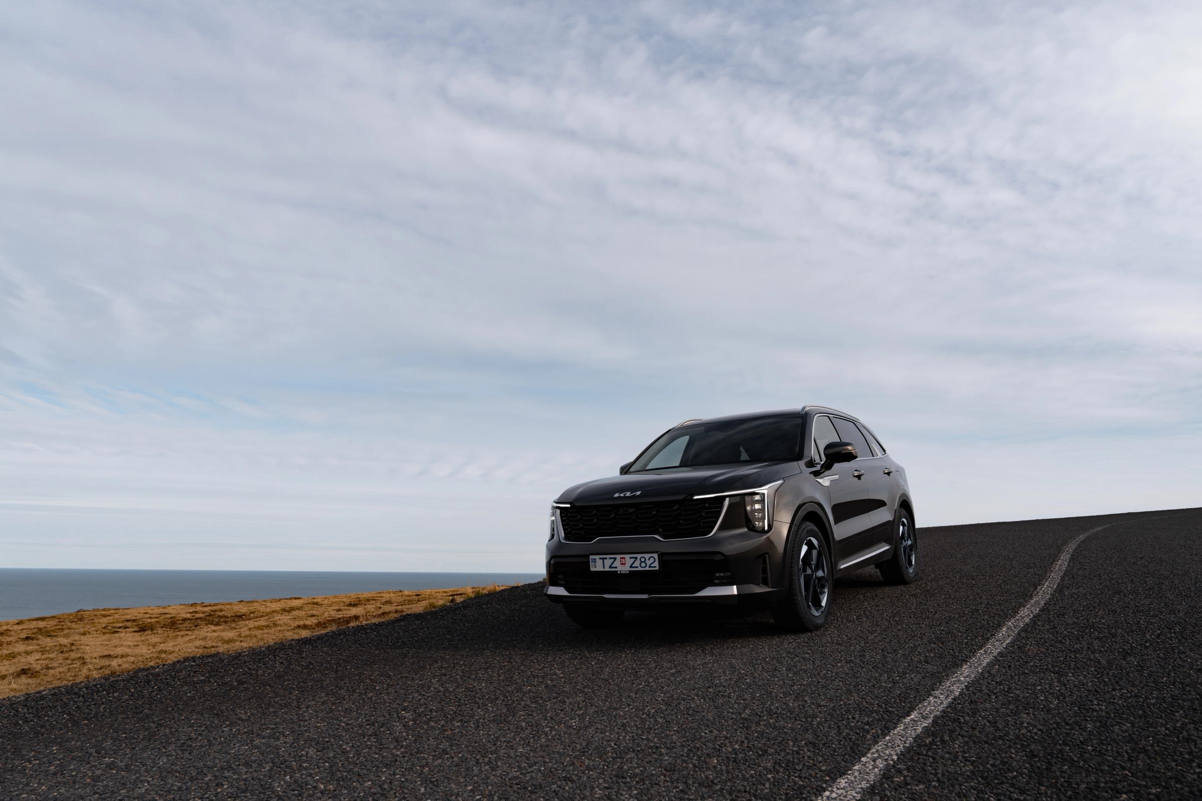 Route côtière de Sorento SUV Kia Sorento de location en Islande roulant sur une route côtière goudronnée surplombant la mer