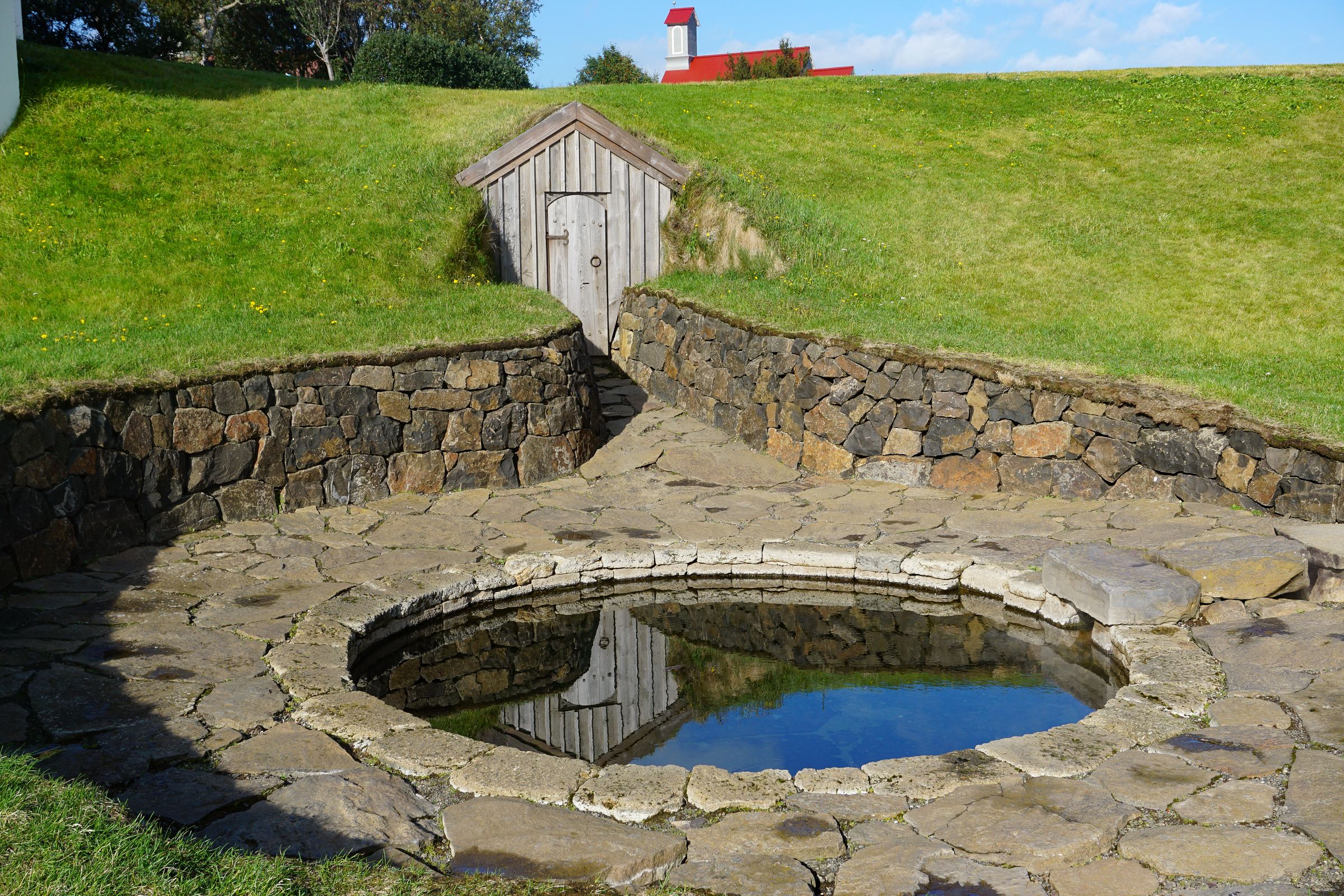 there is a small pond in the middle of a stone wall at snorralaug in iceland.